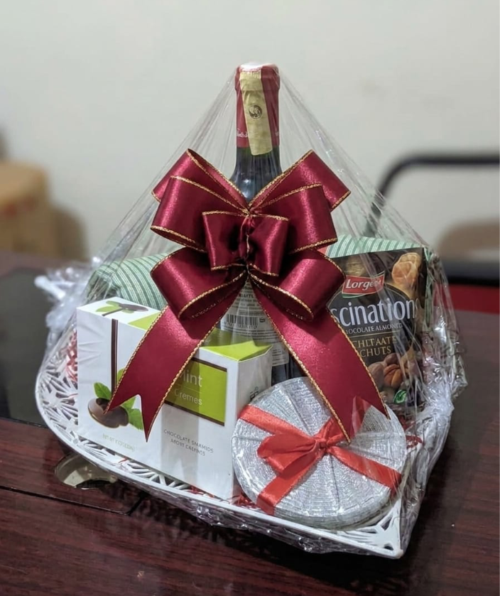 Cellophane-wrapped wine hamper with chocolates and a red satin bow